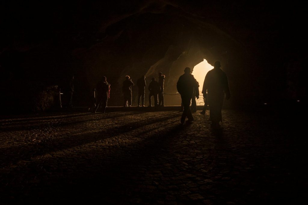 A group of silhouettes in the cave entrance backlit by sunlight in Tangier, Morocco.